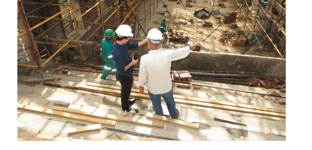 Two men in construction hard hats overlooking a construction site