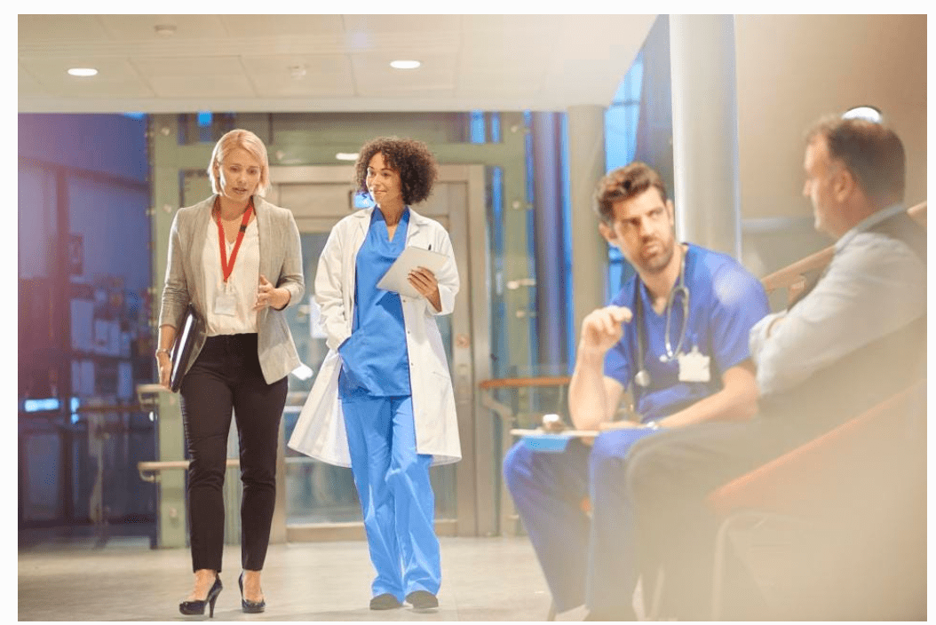 Pharmaceutical sales rep walking and talking with a clinician in a hospital