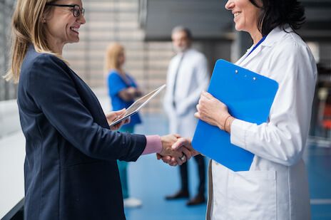 Two women smiling and shaking hands after a successful meeting