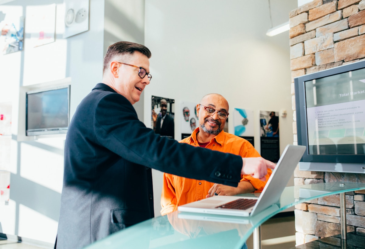 Two businessmen chatting over a laptop about sales strategies